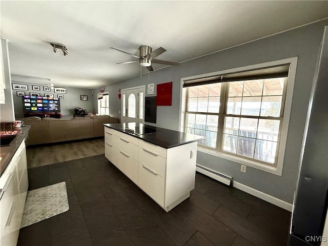 kitchen with black electric stovetop, ceiling fan, white cabinets, and baseboard heating