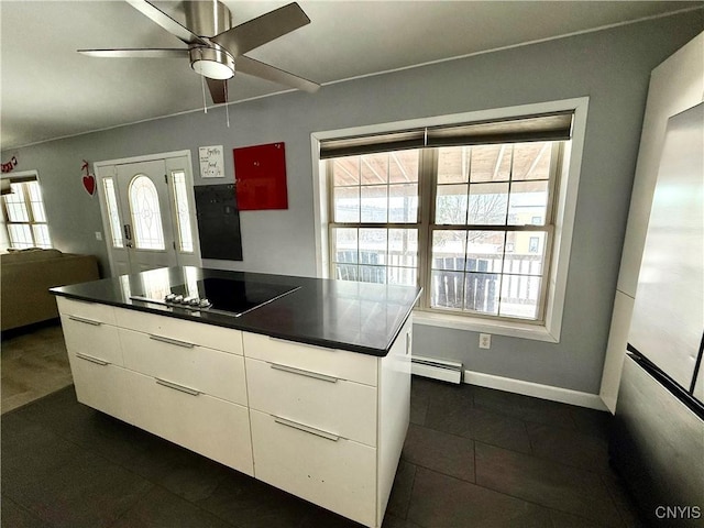 kitchen with black electric stovetop, ceiling fan, white cabinets, and a baseboard heating unit