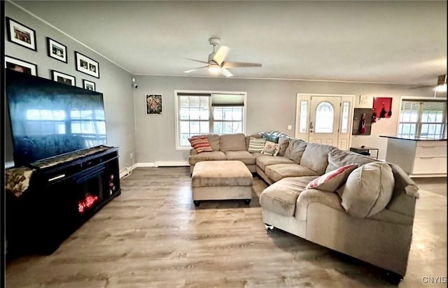 living room with ceiling fan, wood-type flooring, and a baseboard heating unit