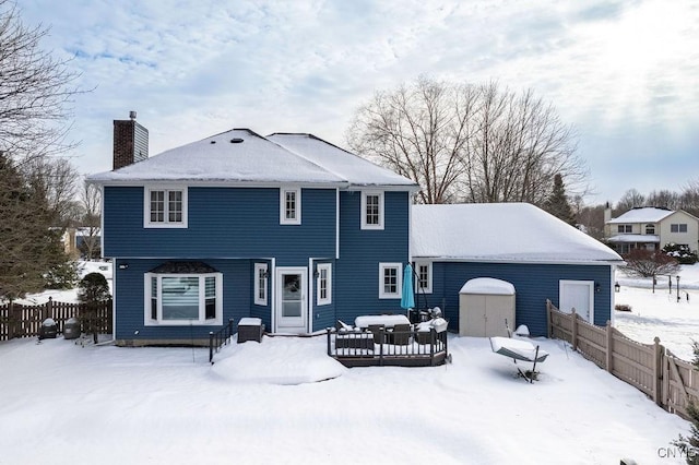 snow covered house featuring a storage unit