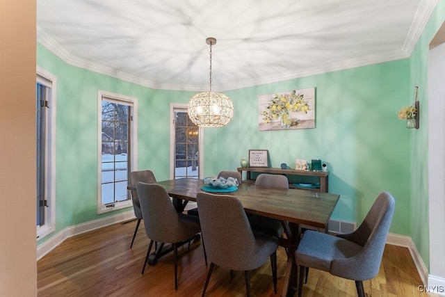 dining area with crown molding, dark hardwood / wood-style flooring, and an inviting chandelier