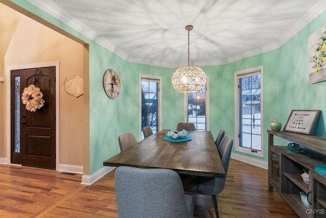 dining space featuring an inviting chandelier, ornamental molding, and dark hardwood / wood-style flooring