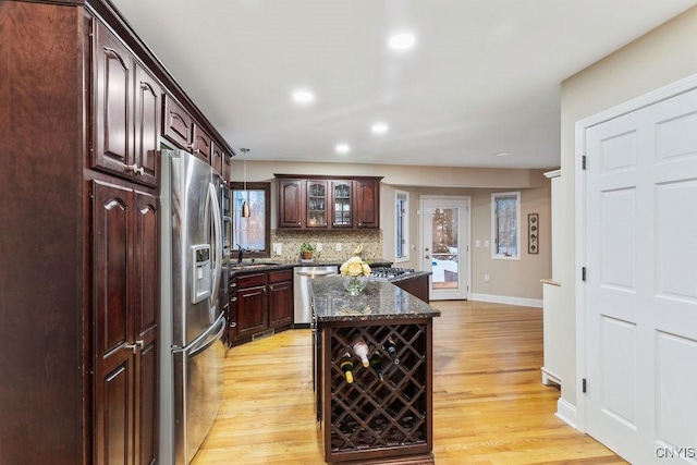 kitchen with stainless steel appliances, a kitchen island, light wood-type flooring, and decorative backsplash