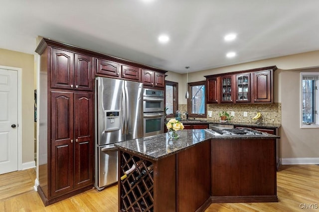 kitchen featuring dark stone countertops, tasteful backsplash, stainless steel appliances, and a kitchen island