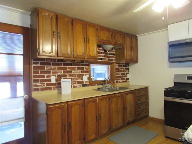 kitchen with appliances with stainless steel finishes, sink, ceiling fan, and light hardwood / wood-style floors