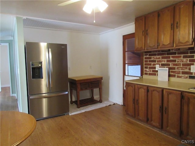 kitchen featuring ceiling fan, crown molding, stainless steel fridge, and light wood-type flooring