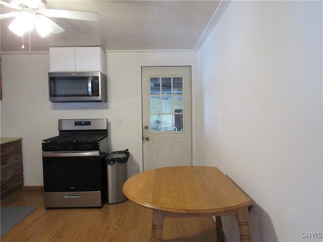 kitchen with white cabinetry, ceiling fan, light hardwood / wood-style floors, stainless steel appliances, and crown molding