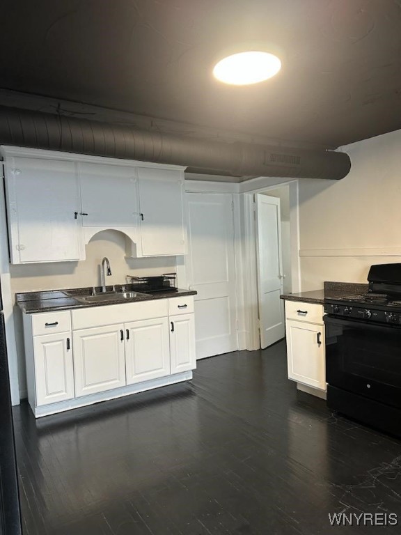 kitchen featuring black gas range, sink, dark hardwood / wood-style flooring, and white cabinets