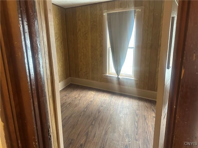 empty room featuring dark wood-type flooring and wooden walls