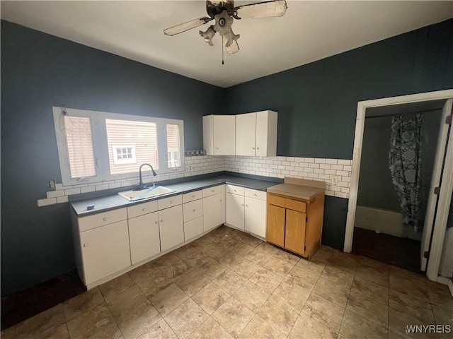 kitchen with white cabinetry, ceiling fan, sink, and backsplash