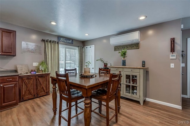 dining room featuring a wall unit AC and light hardwood / wood-style flooring