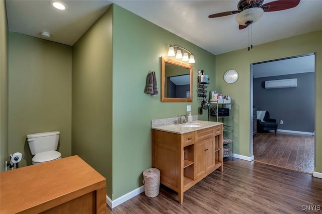 bathroom with wood-type flooring, an AC wall unit, vanity, and ceiling fan