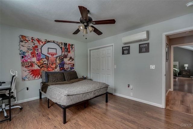 bedroom featuring ceiling fan, a wall mounted air conditioner, and wood-type flooring