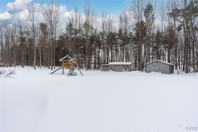 snowy yard with a storage unit and a playground