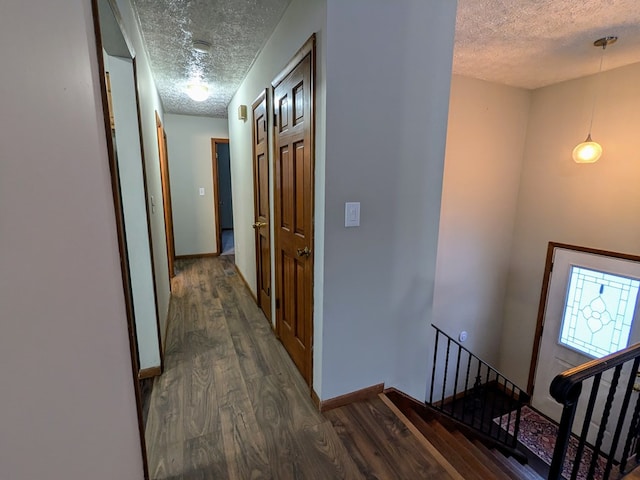 corridor with dark hardwood / wood-style floors and a textured ceiling