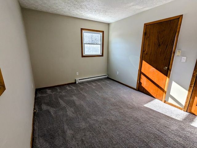 empty room with dark colored carpet, a textured ceiling, and baseboard heating