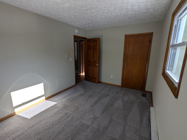 unfurnished bedroom featuring a baseboard radiator, a textured ceiling, and carpet