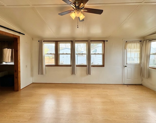 spare room with lofted ceiling, a healthy amount of sunlight, and light hardwood / wood-style flooring