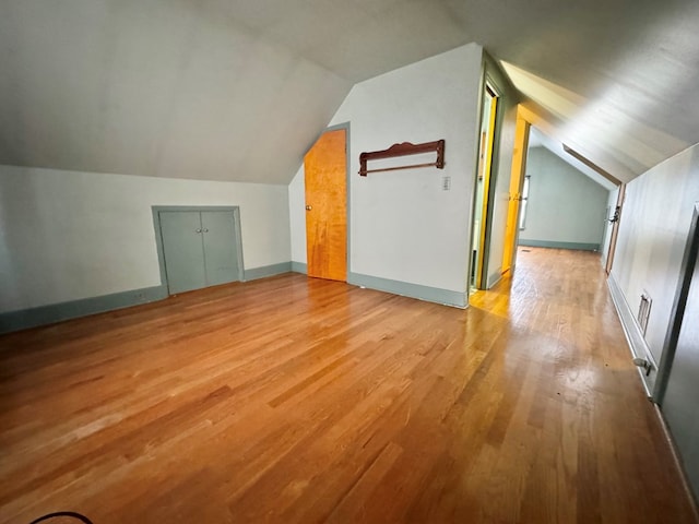 additional living space with light hardwood / wood-style flooring and vaulted ceiling