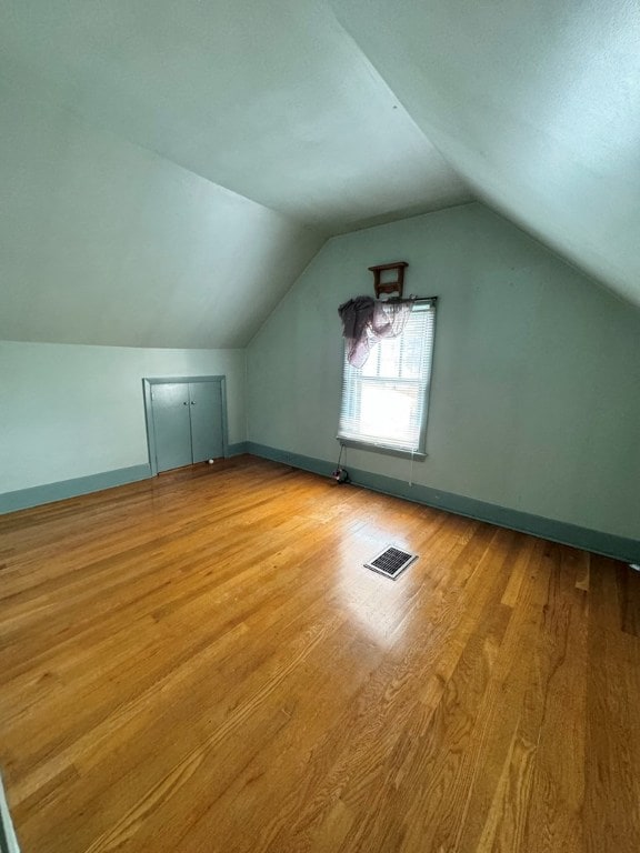 additional living space with vaulted ceiling and light wood-type flooring