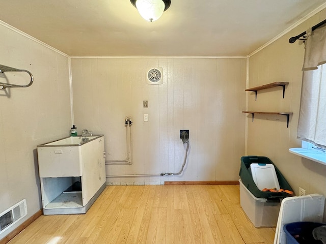 clothes washing area with light hardwood / wood-style flooring and ornamental molding