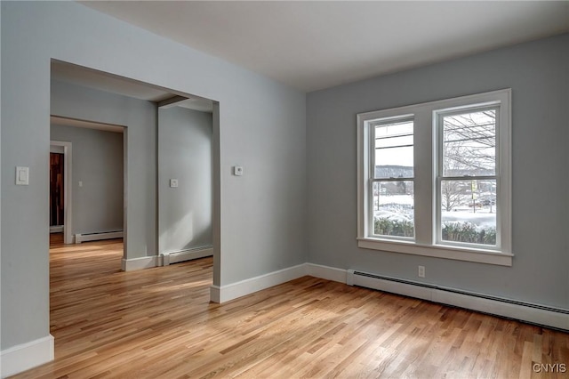 unfurnished room featuring a baseboard radiator and light hardwood / wood-style floors