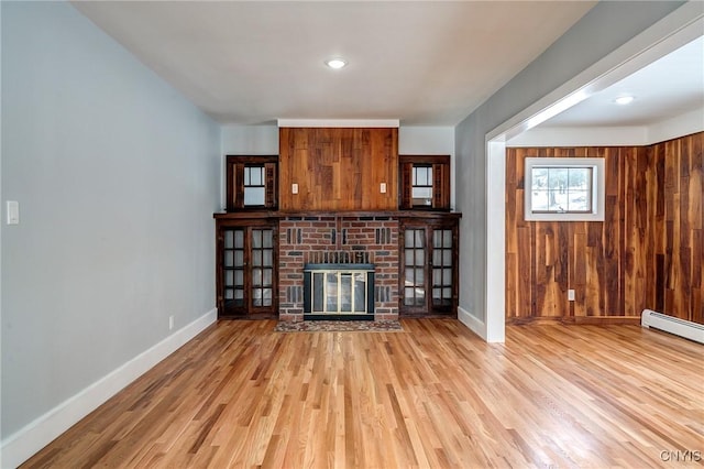 unfurnished living room with a fireplace, light hardwood / wood-style floors, and baseboard heating