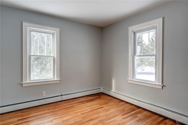 empty room with a baseboard heating unit and light hardwood / wood-style floors