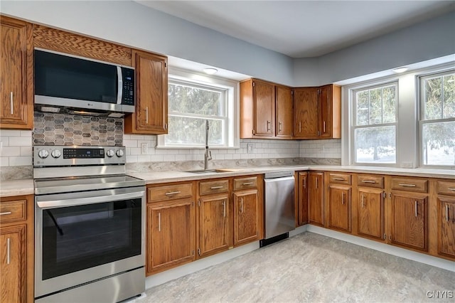 kitchen with sink, backsplash, stainless steel appliances, and a healthy amount of sunlight