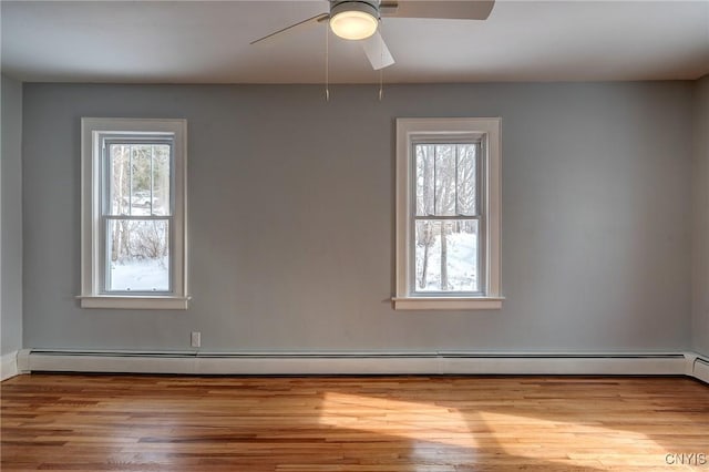 unfurnished room with light wood-type flooring, a wealth of natural light, ceiling fan, and baseboard heating