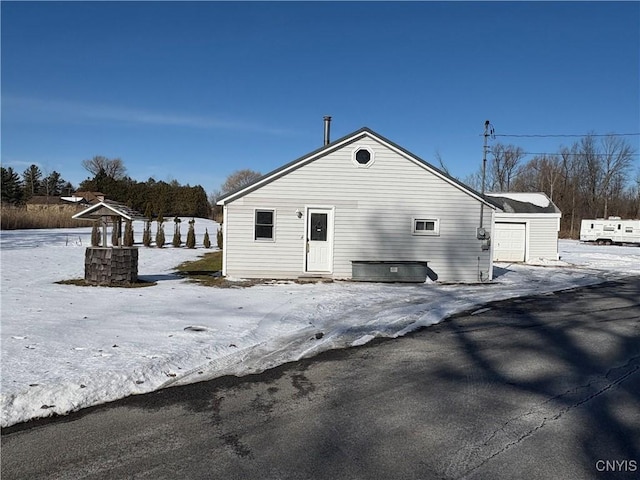 snow covered rear of property featuring a garage