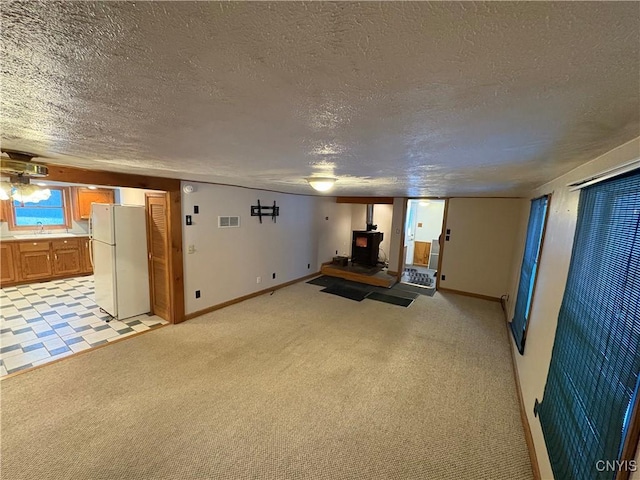 interior space with white fridge, sink, light colored carpet, and a wood stove