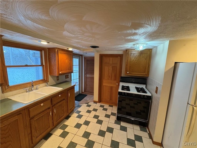 kitchen featuring sink, range with gas cooktop, a textured ceiling, and white fridge