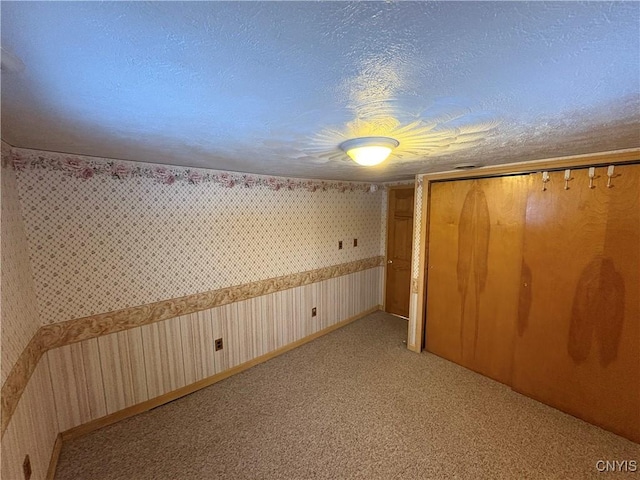 interior space with light colored carpet, a closet, and a textured ceiling