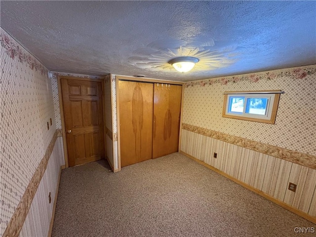 unfurnished bedroom featuring ceiling fan, light colored carpet, a textured ceiling, and a closet