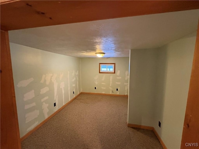 basement featuring light colored carpet and a textured ceiling