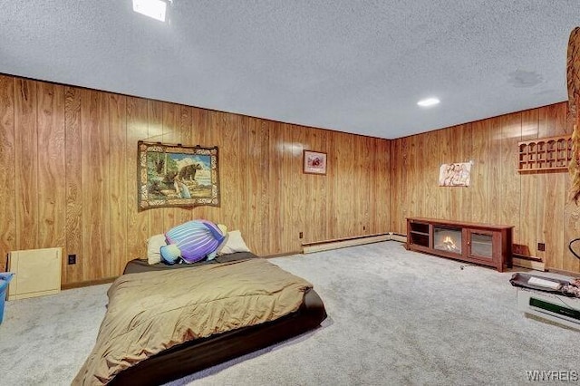 carpeted bedroom featuring wooden walls, a textured ceiling, and baseboard heating