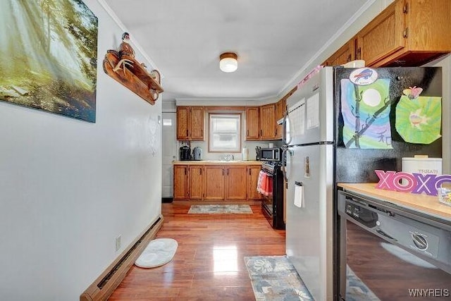 kitchen featuring crown molding, a baseboard heating unit, light hardwood / wood-style flooring, and black appliances