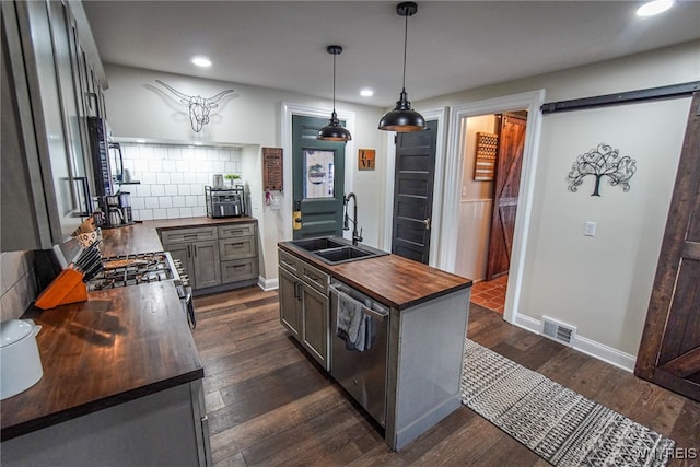 kitchen with dark hardwood / wood-style floors, butcher block countertops, sink, hanging light fixtures, and stainless steel dishwasher