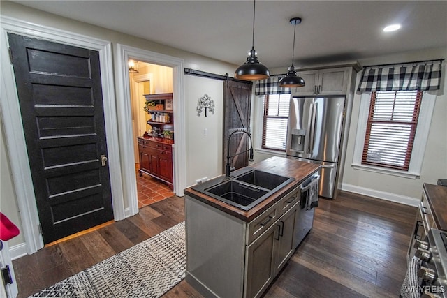 kitchen featuring sink, appliances with stainless steel finishes, gray cabinetry, decorative light fixtures, and a barn door