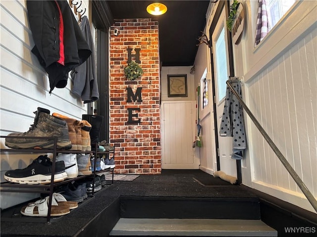 mudroom featuring brick wall