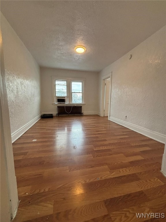 spare room featuring radiator, hardwood / wood-style floors, and a textured ceiling