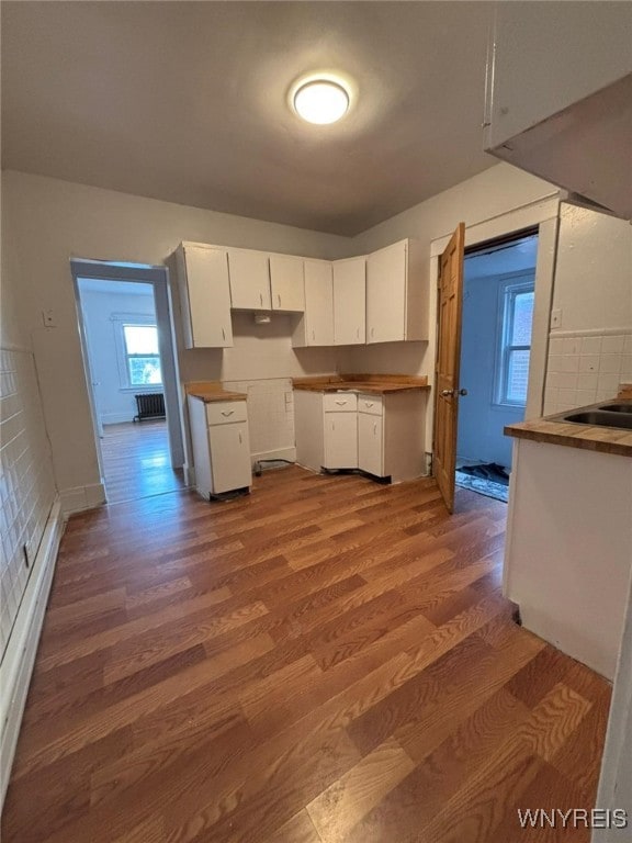 kitchen with hardwood / wood-style floors, backsplash, and white cabinets