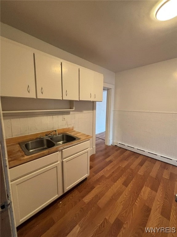 kitchen featuring sink, butcher block counters, white cabinets, dark hardwood / wood-style flooring, and a baseboard radiator