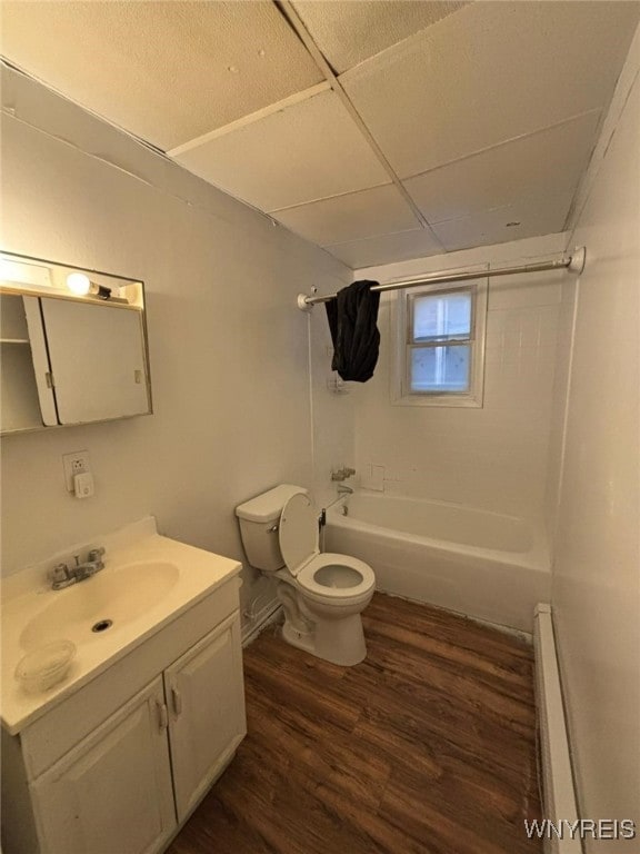 full bathroom featuring hardwood / wood-style flooring, a baseboard heating unit, vanity, tiled shower / bath, and toilet