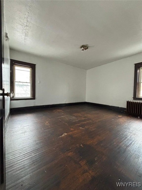 unfurnished room featuring dark wood-type flooring and radiator heating unit