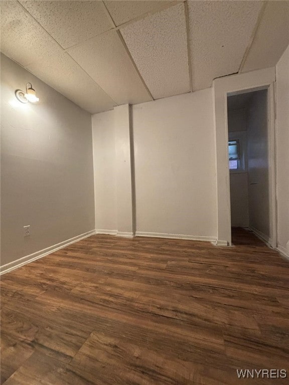 empty room with dark hardwood / wood-style floors and a drop ceiling