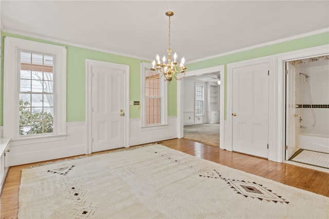 unfurnished dining area with ornamental molding, a chandelier, and light hardwood / wood-style floors