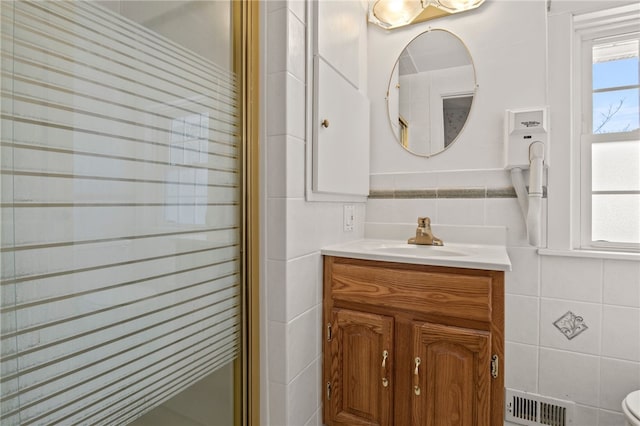 bathroom with walk in shower, vanity, and tile walls