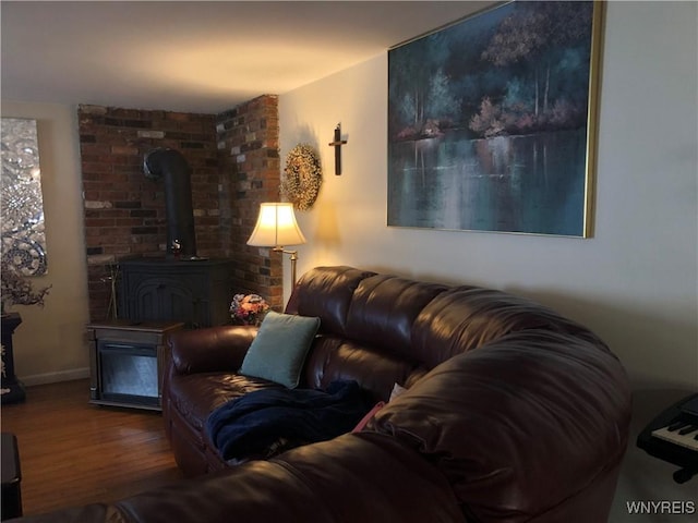 living area with a wood stove, baseboards, and wood finished floors